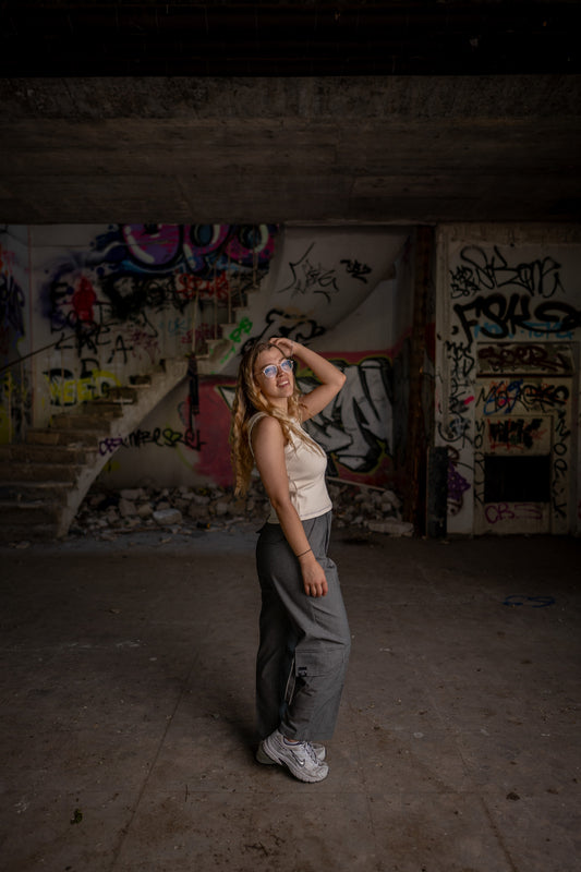 Aufnahme eines Models mit Jeanshose. Das Model blickt an ihrer rechten Schulter vorbei in die Kamera und lächelt. ihren linken Arm hat sie lässig an den Kopf gehoben.