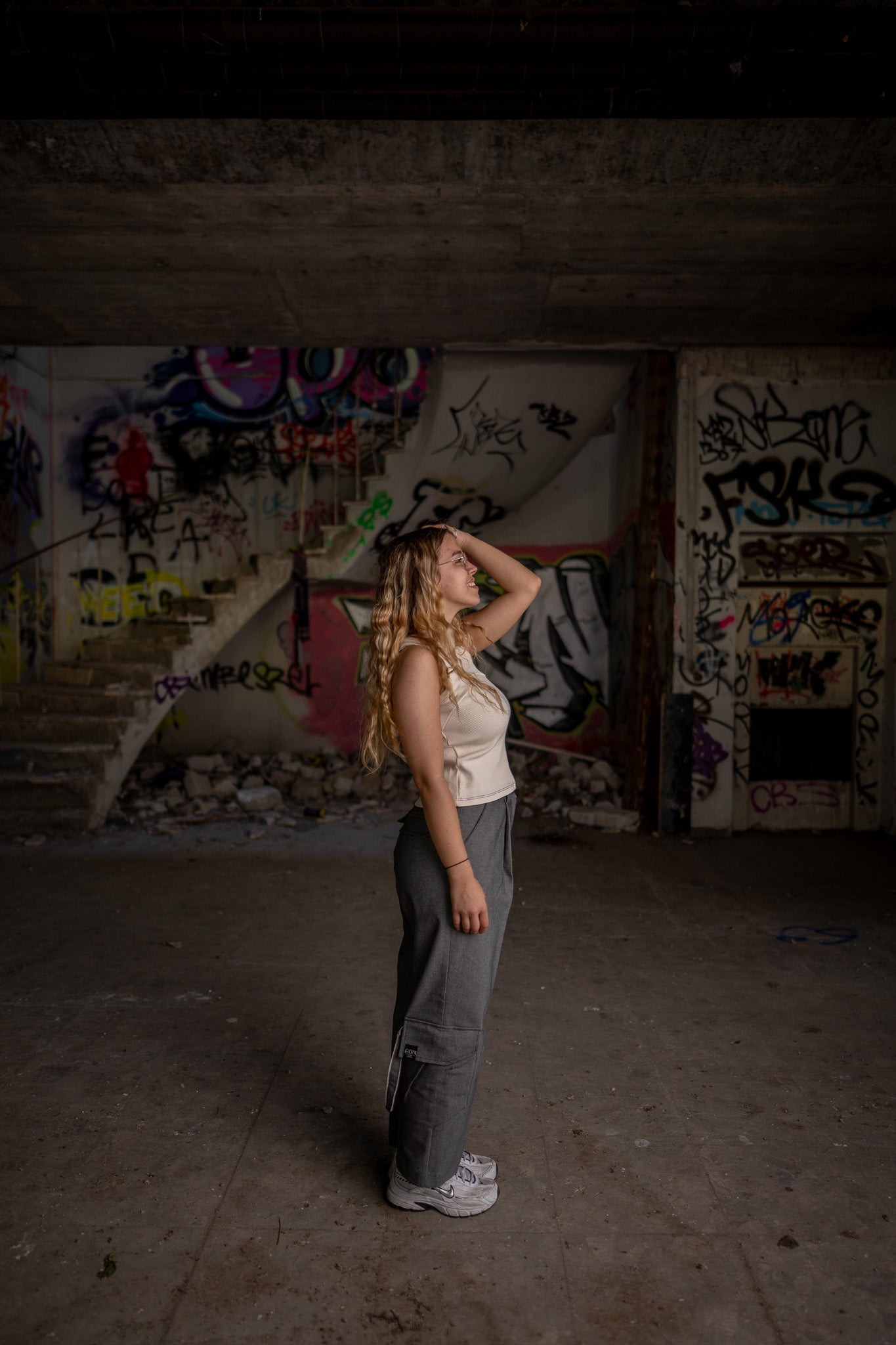 Seitliche Aufnahme des Models, das die Jeanshose von Claire Common trägt. Das Model hat wieder den linken Arm zum Kopf gehoben. Es blickt nicht in die Kamera und lächelt zufrieden.