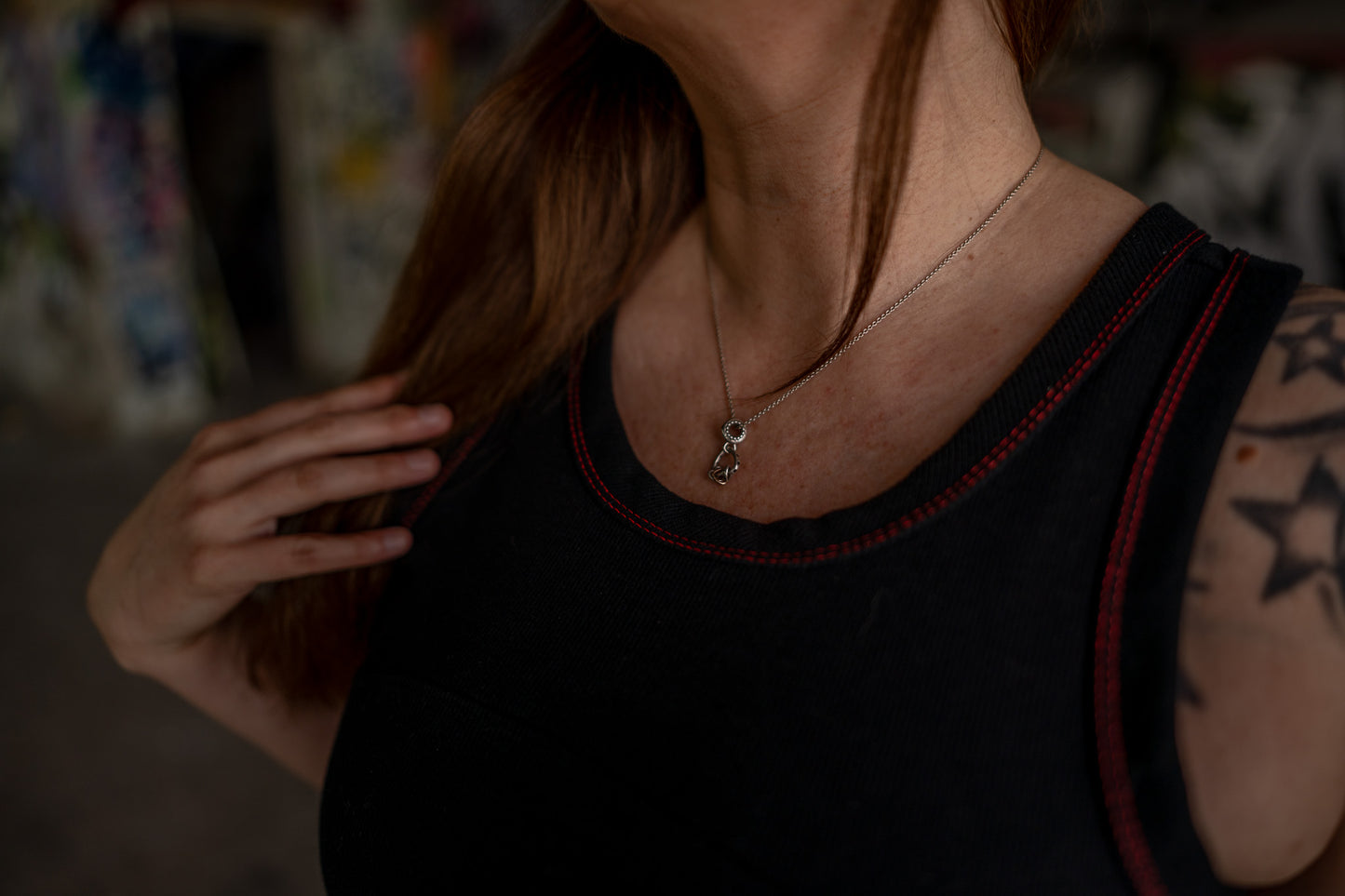 Das schwarze Tanktop mit roten Nähten ist in Nahaufnahme zu sehen am oberen Ausschnitt des Oberteils. Man sieht genau die Nahtdetails.